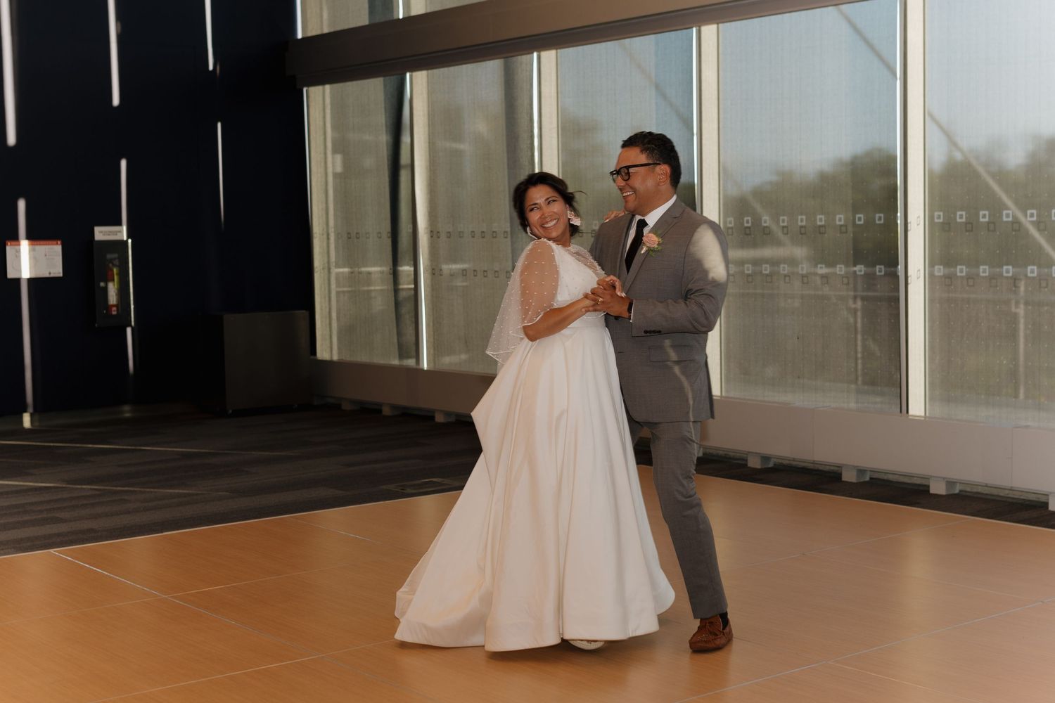 A couple shares their first dance together on a modern indoor dance floor at their wedding celebration.
