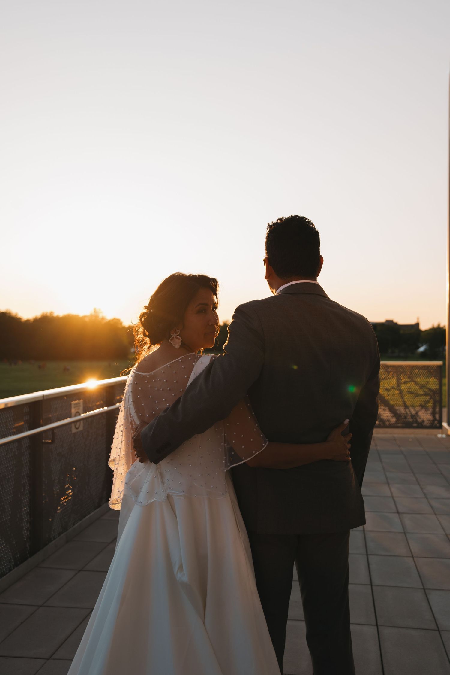 A couple embraces on a rooftop terrace at sunset, creating a romantic silhouette against the golden sky.