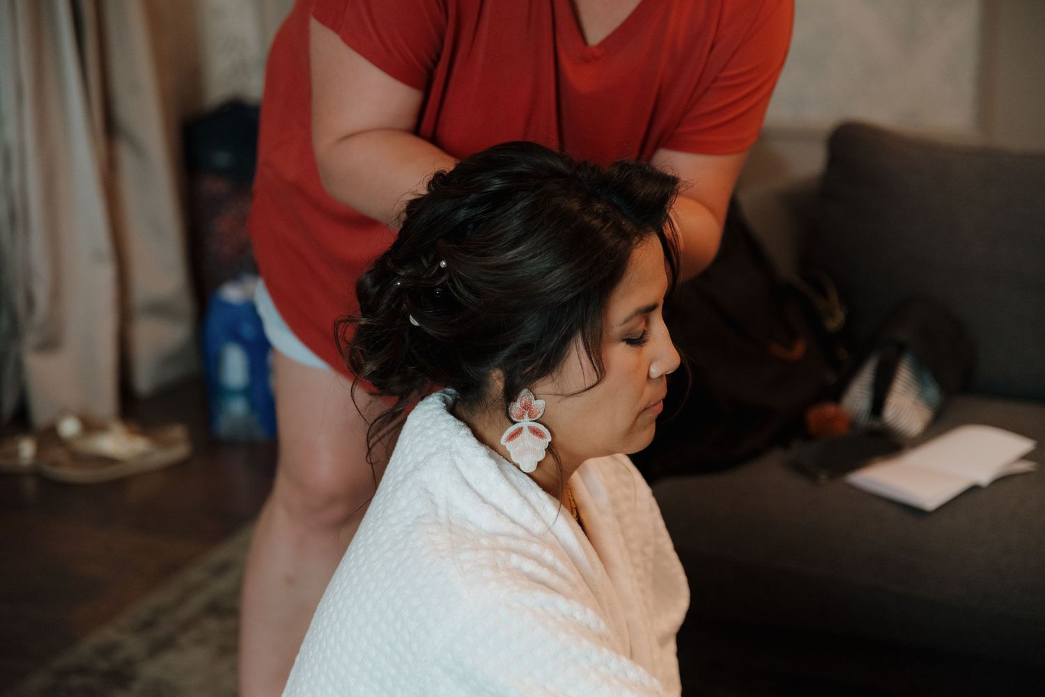 Wedding day preparation scene with someone getting their hair styled while wearing a white robe.