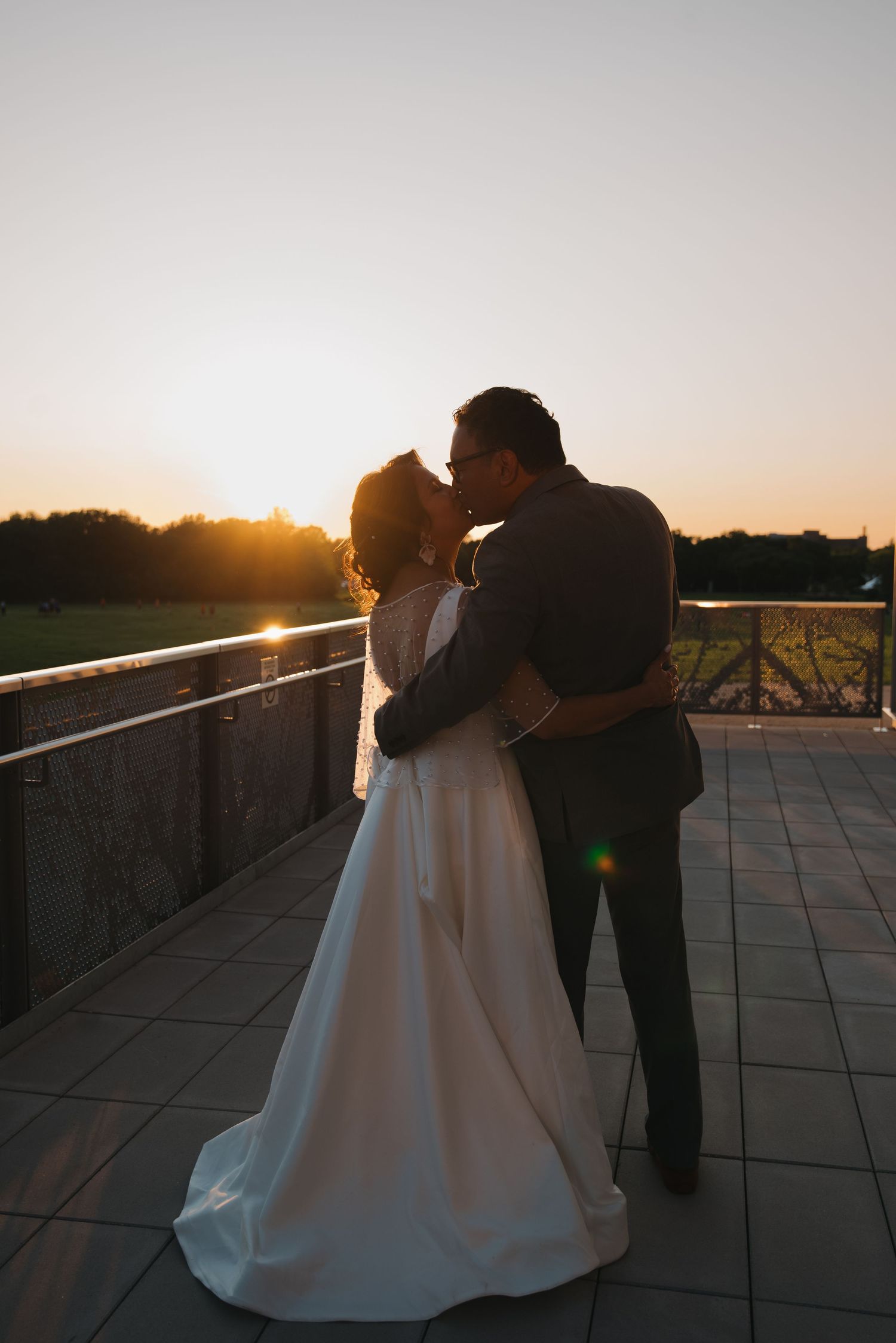 Silhouetted couple shares a romantic sunset kiss on an outdoor terrace.