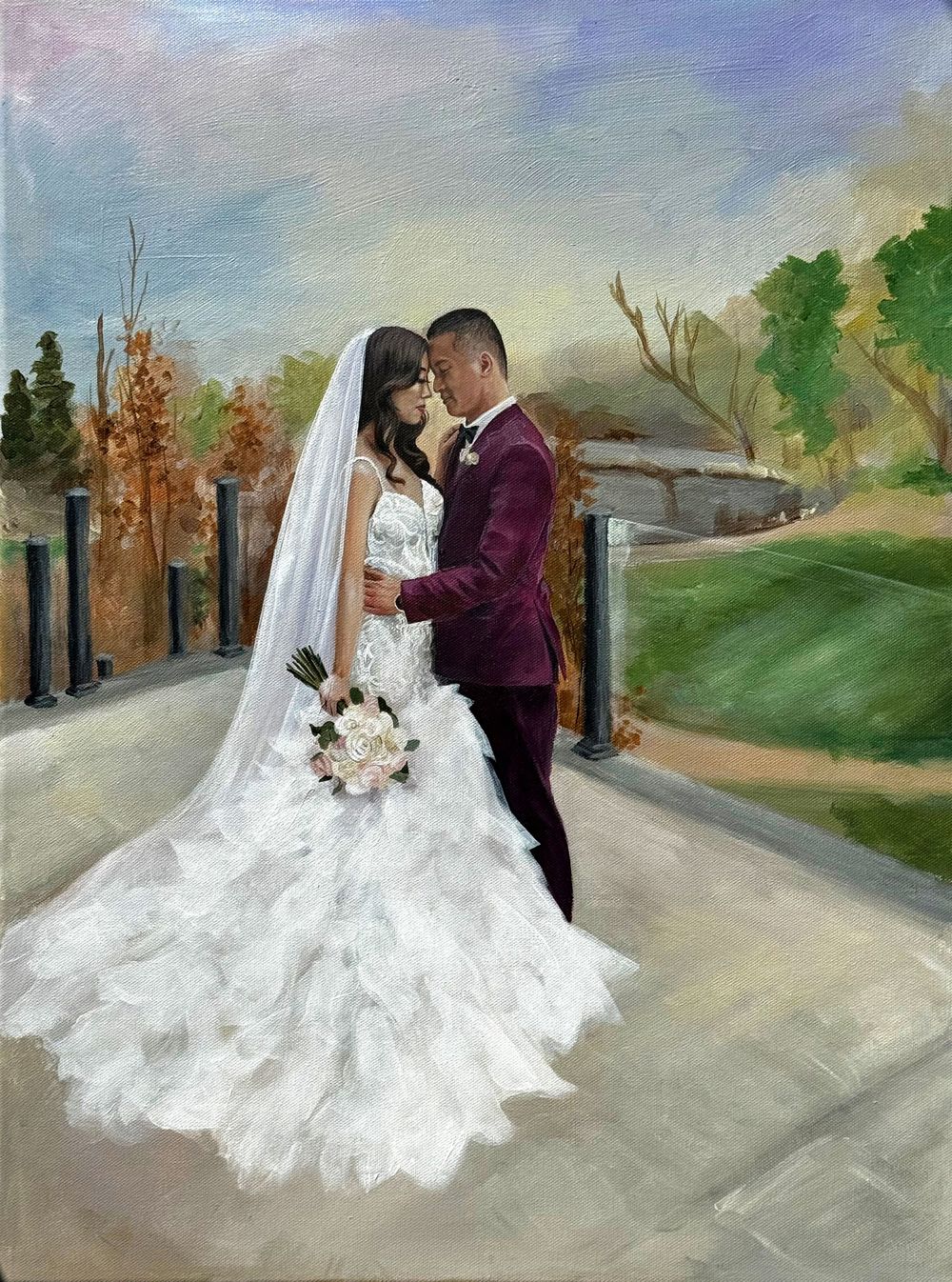 A couple shares an intimate moment in their wedding attire by a scenic outdoor path with autumn trees in the background.