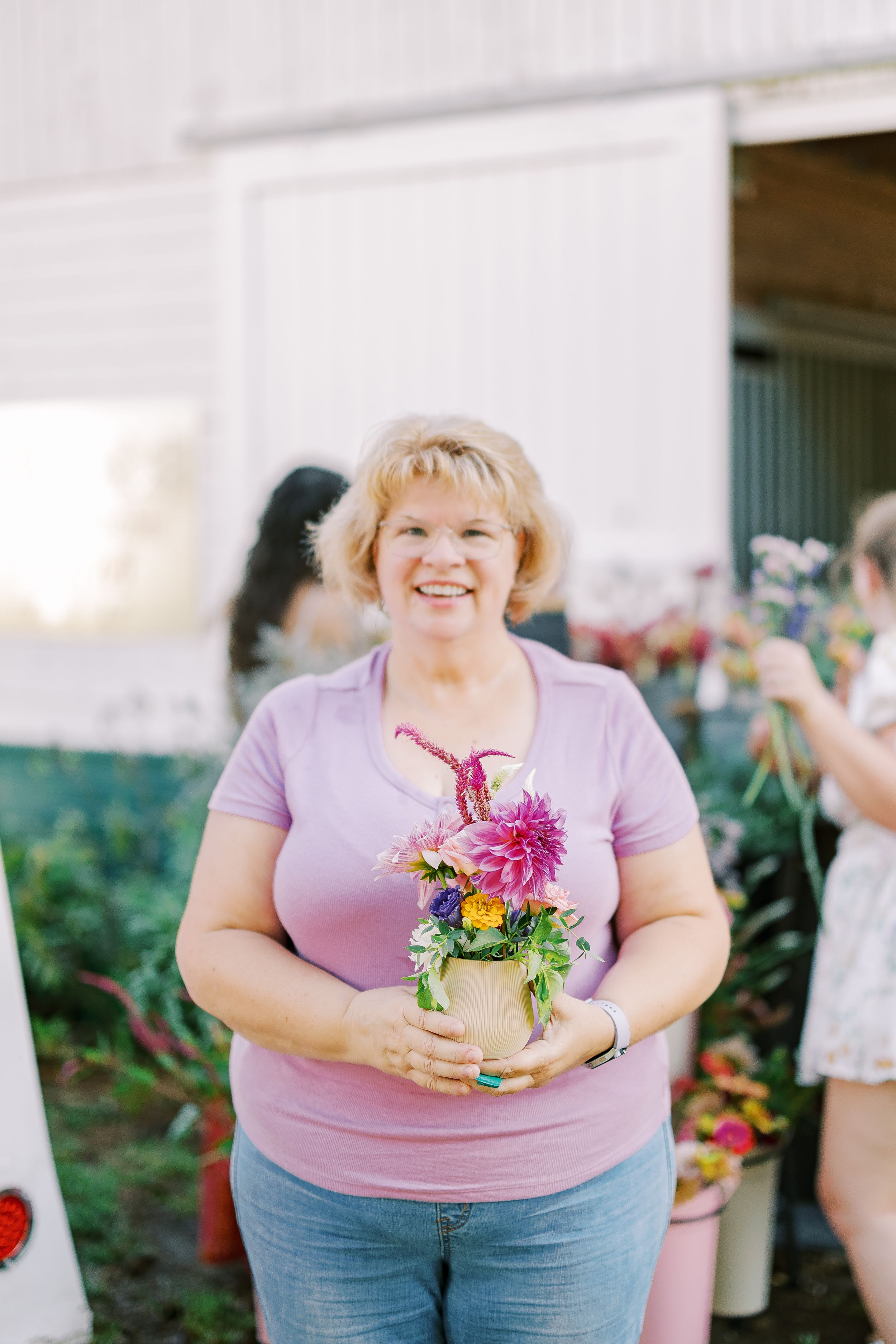 A cheerful scene at a flower shop with someone holding a vibrant bouquet of pink and yellow flowers.