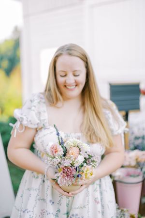 A series of shots showing someone holding a delicate bouquet of mixed pastel flowers in a floral dress.