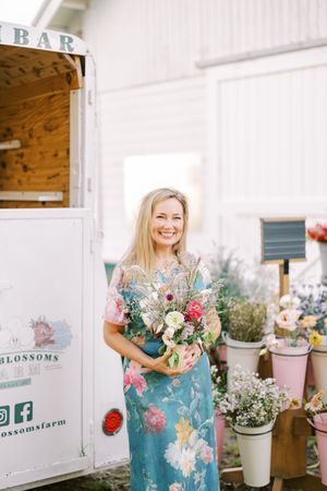 A collection of floral arrangements and displays shown at a rustic flower shop called Blossoms.