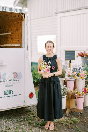 A black-dressed florist arranges colorful fresh bouquets outside of a white mobile flower truck called M Bar.