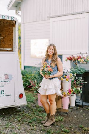 Summer floral display at a mobile flower bar with buckets of fresh blooms against white barn.