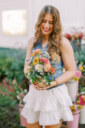Fresh floral arrangements in bright summer colors held against a flowing white eyelet dress.