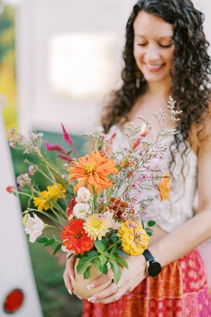 Colorful bouquets featuring orange dahlias and yellow flowers arranged in a garden setting.