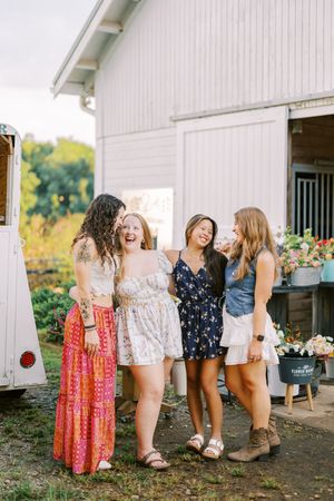 Group enjoying laughter together at outdoor flower market by white barn.