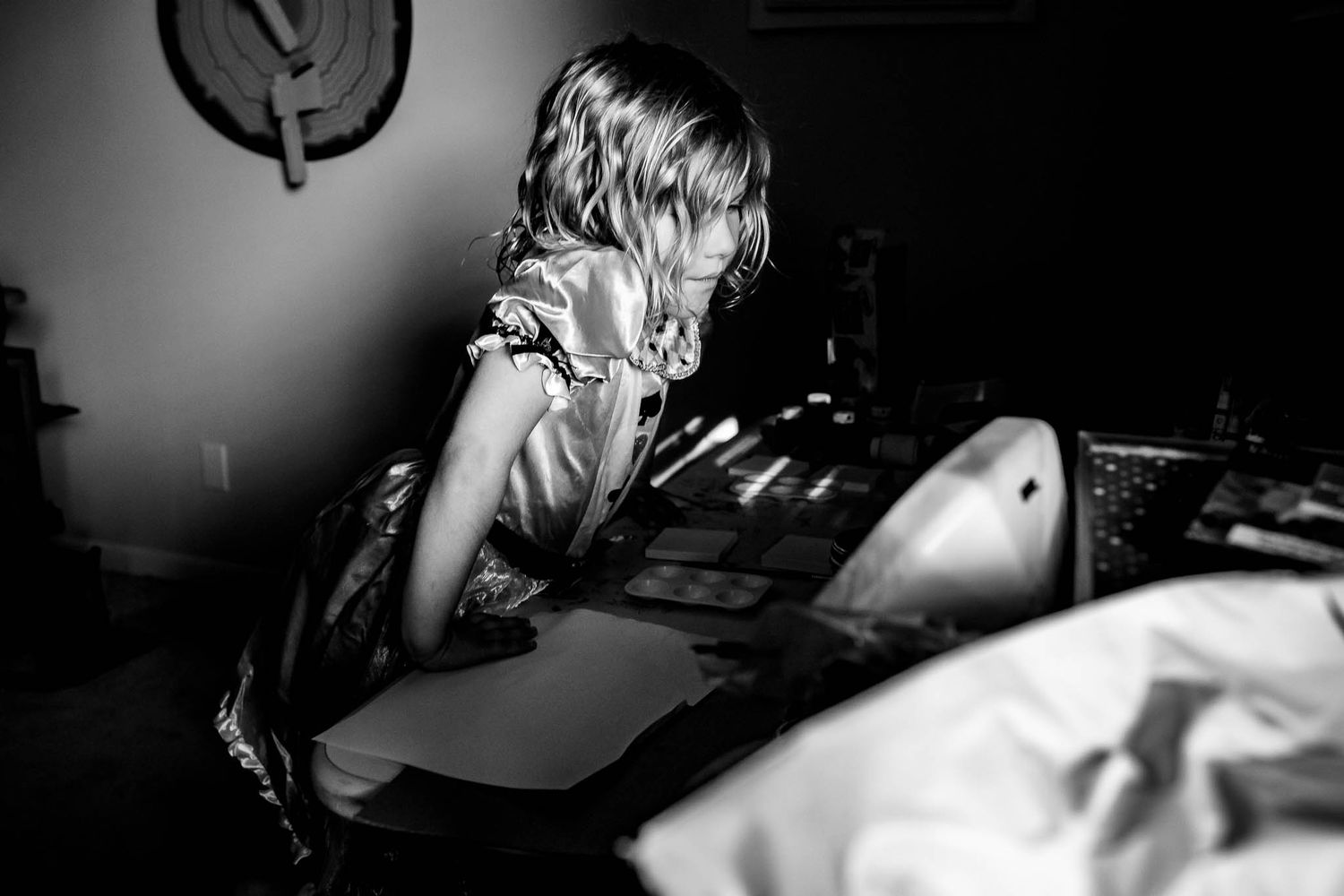 A dramatic black and white photo of someone looking down at a surface in low key lighting.