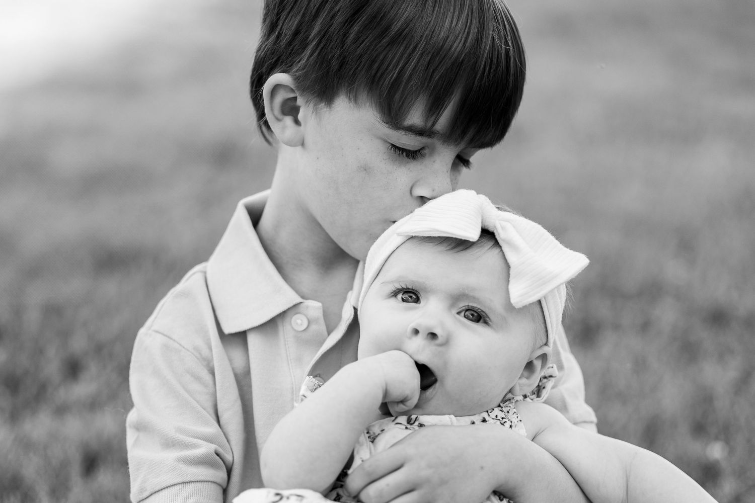Central Illinois family photographer captures young boy kissing his sister's head in black & white during a photo session in Springfield, IL