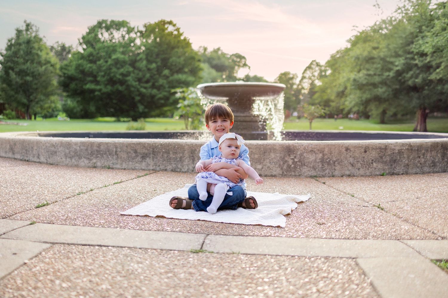 Central Illinois family photographer captures siblings smiling in from of a fountain during a photo session in Springfield, IL