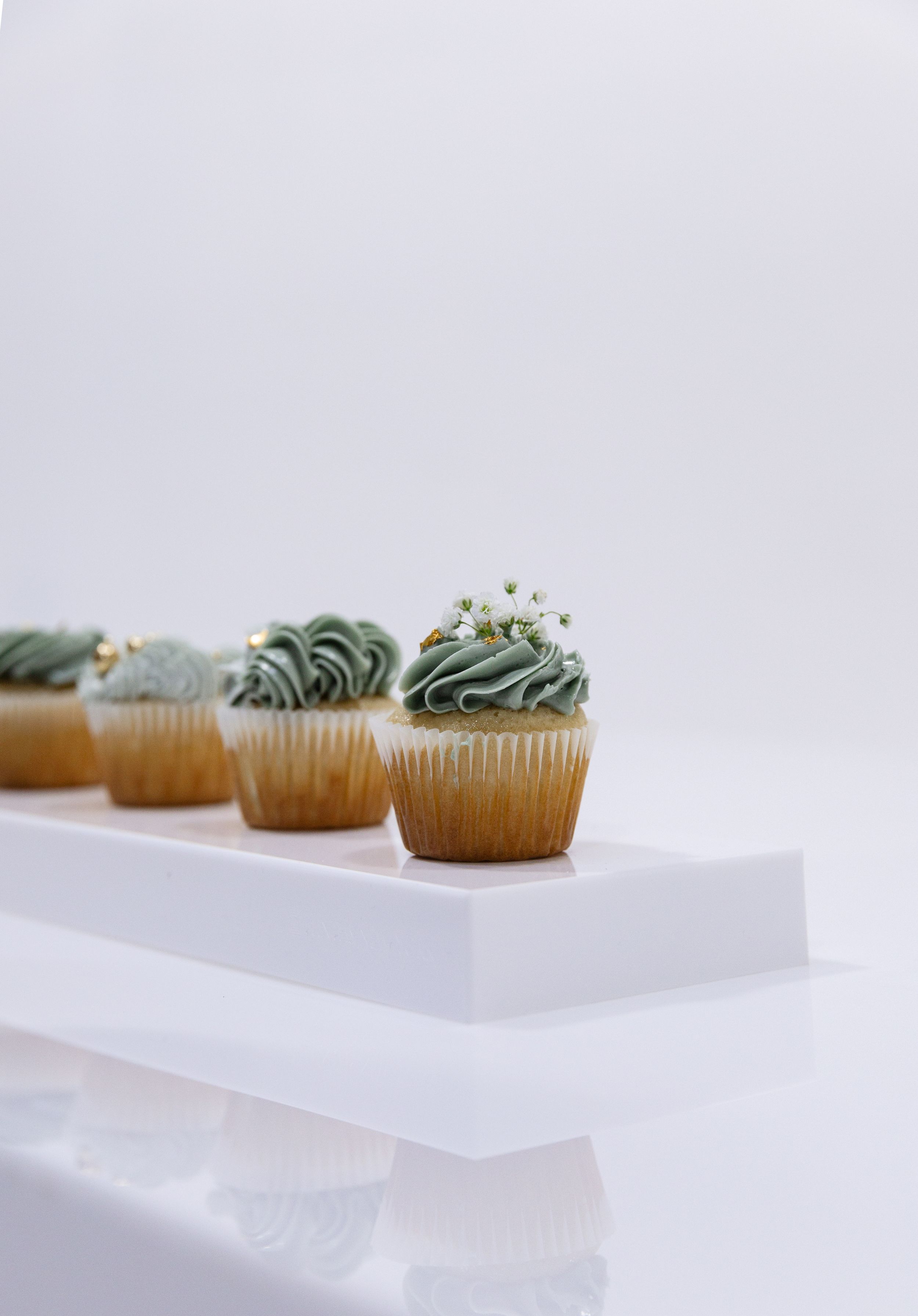 Elegant mint green frosted cupcakes arranged on a white surface with minimalist styling.