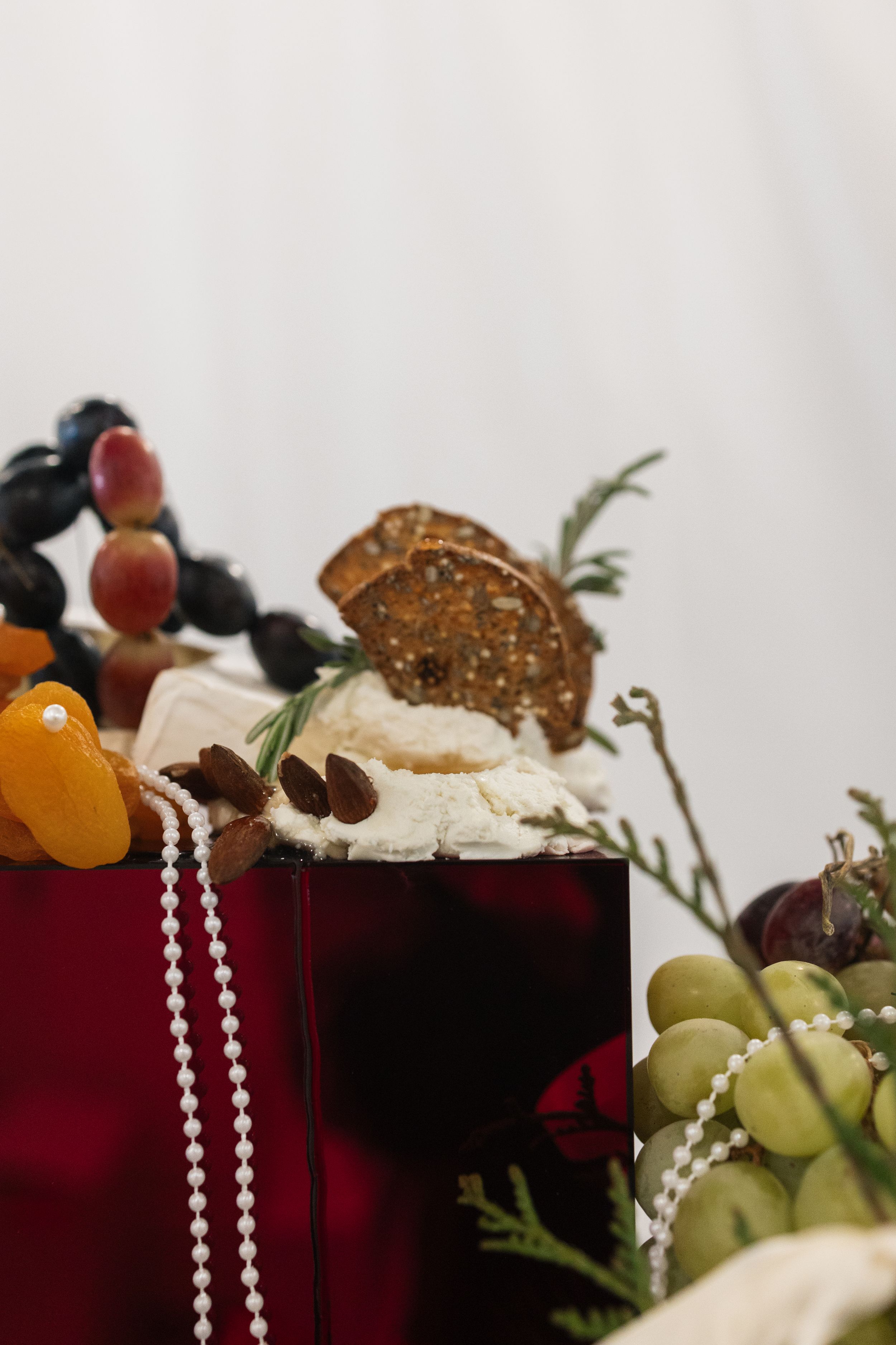 Gourmet dessert display with fresh fruits, pearls, and chocolate garnish on red velvet.