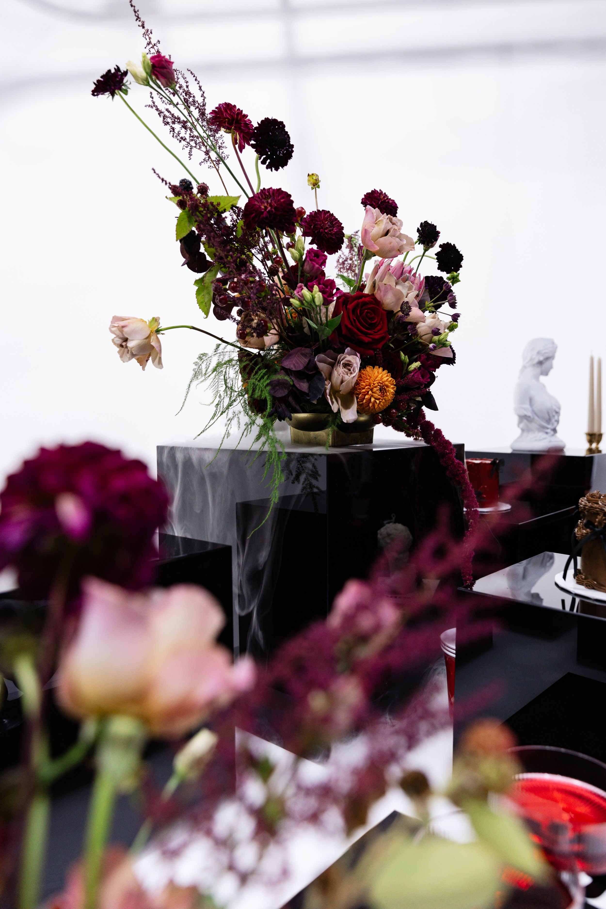 Dramatic floral arrangement with deep purple and pink blooms in moody lighting.