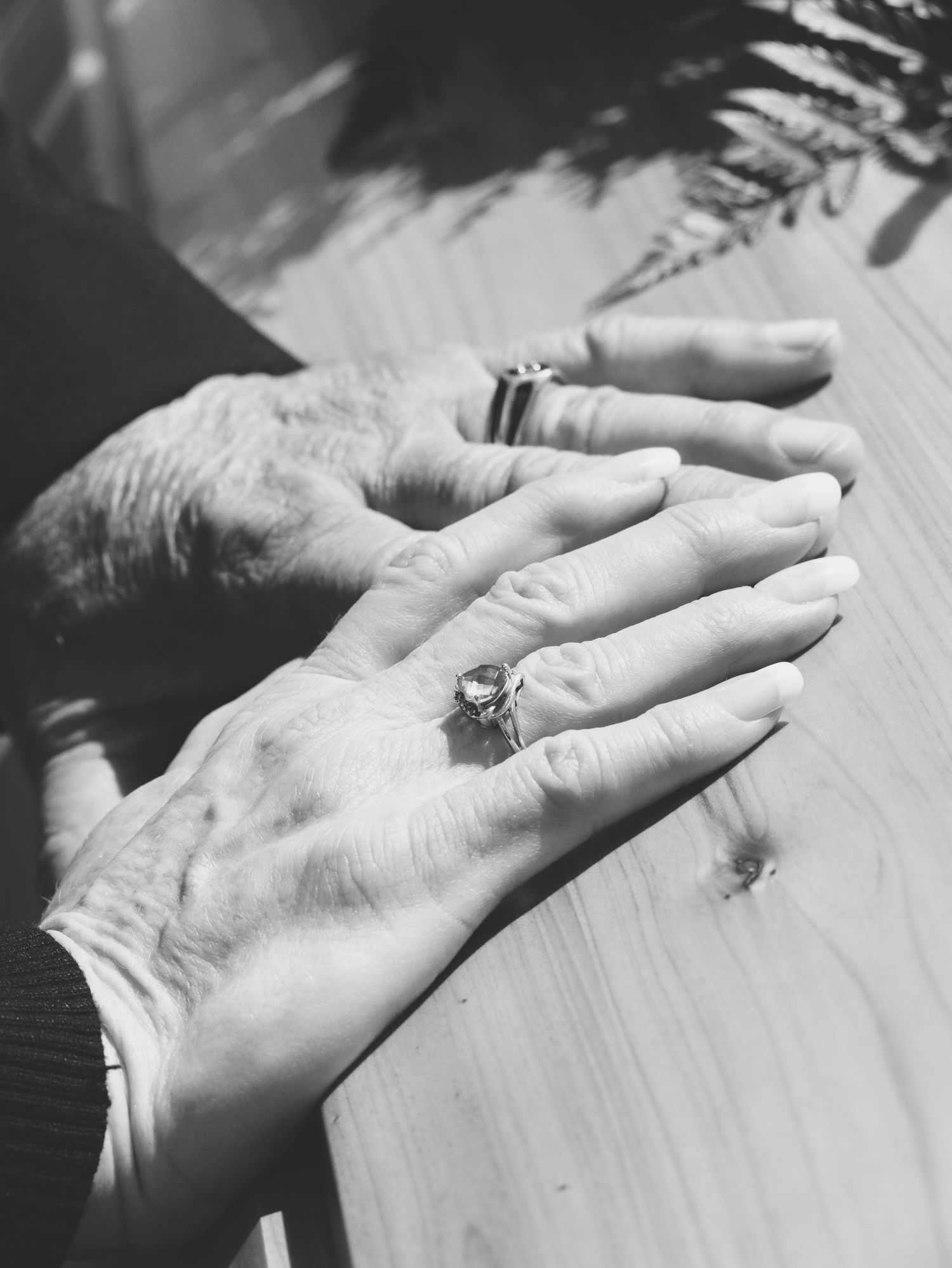 A father and mother's hands resting on the top of the casket of their son