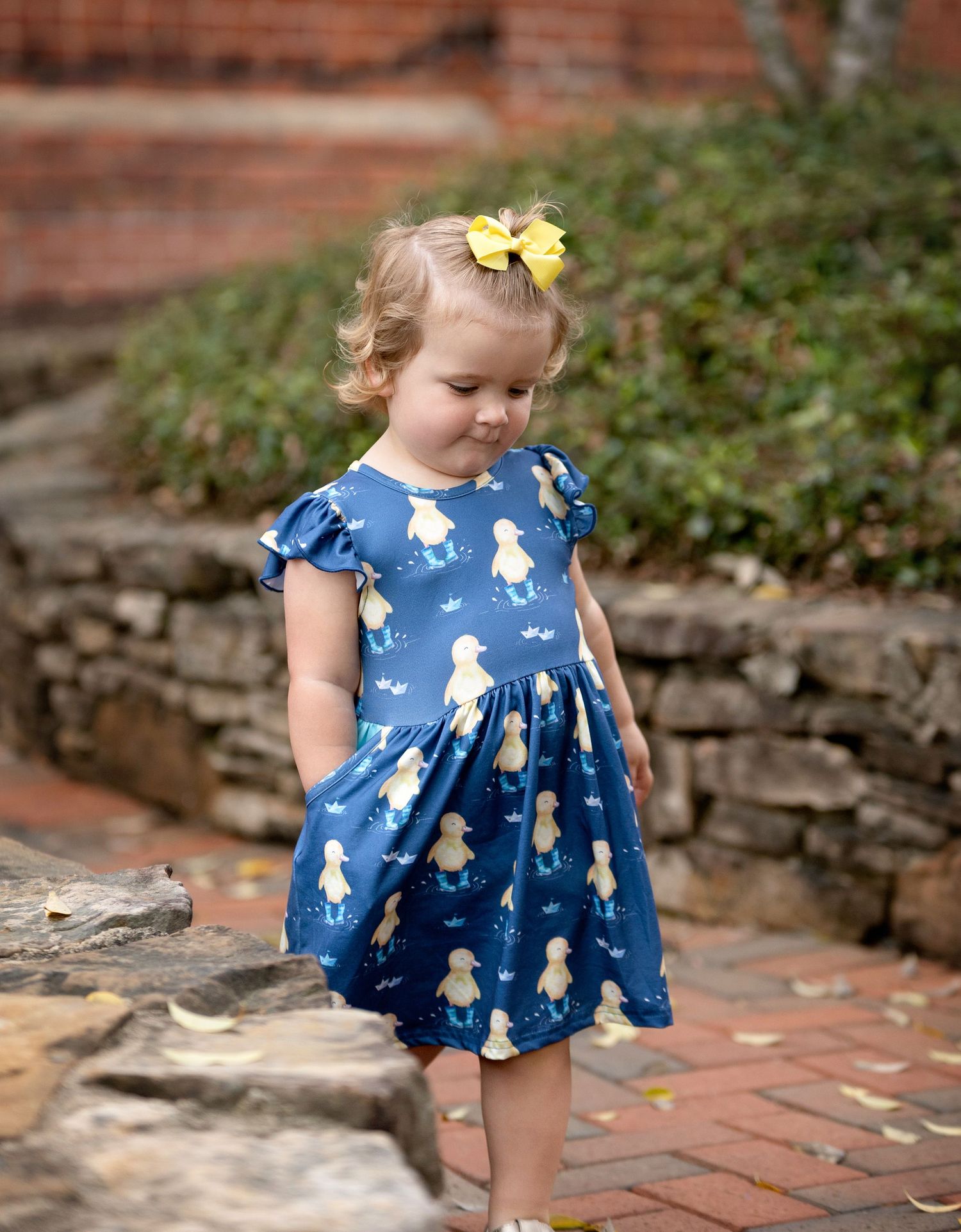A two-year-old little girl with curls holding her duck in a duck dress. Greenville, SC newborn photographer. Easley, SC Newborn photographer