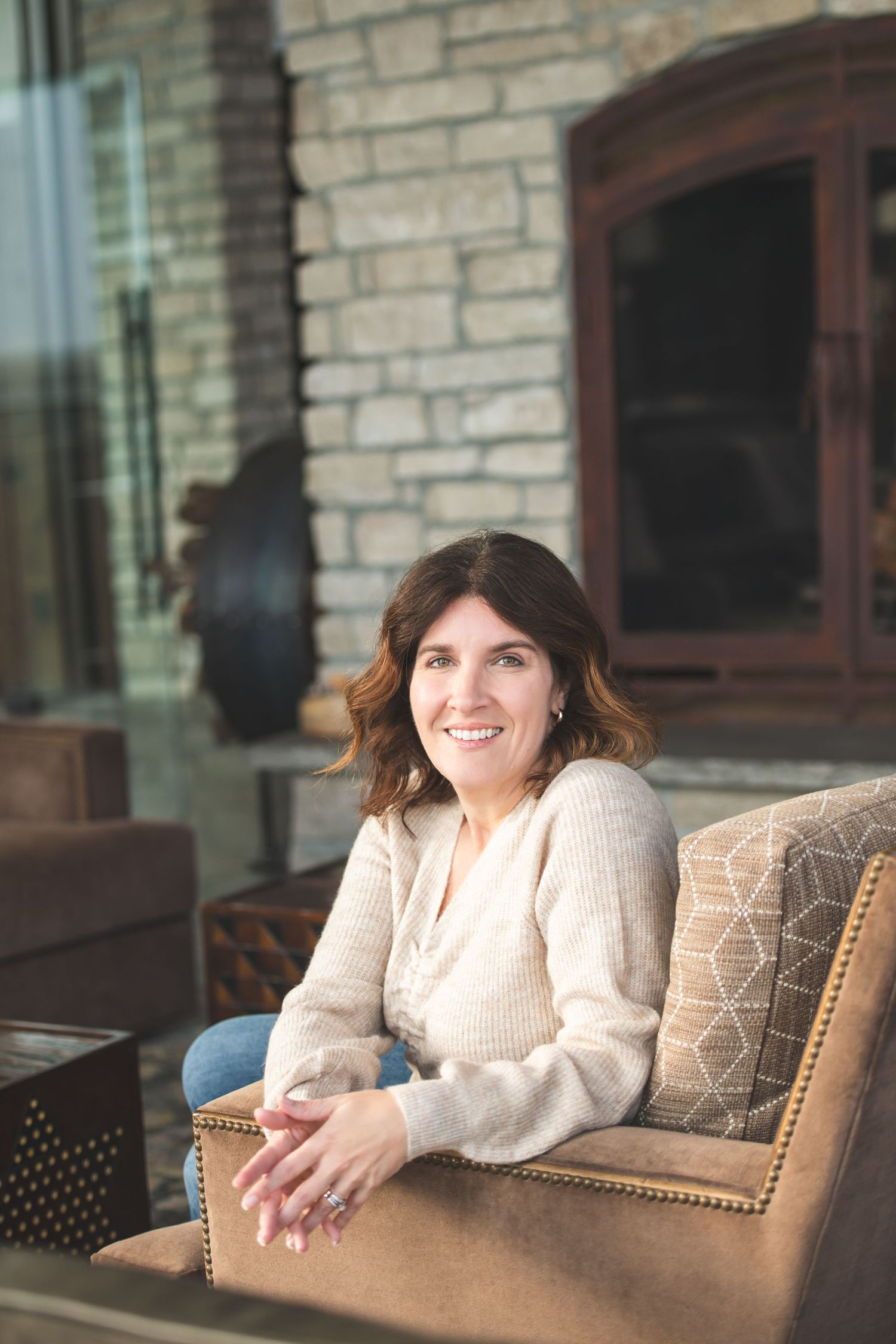 Woman relaxing in comfortable armchair against brick wall background.