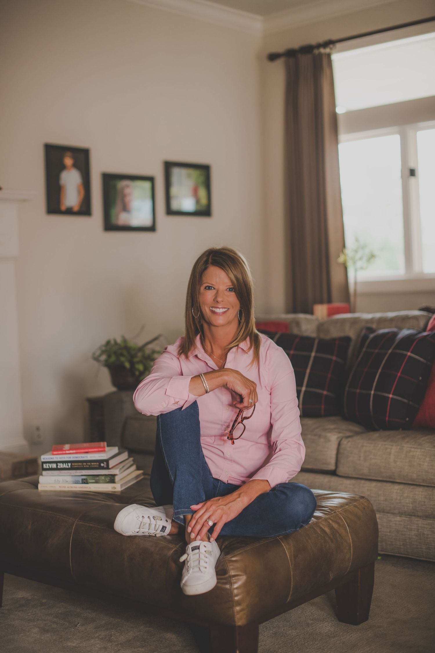 Casual portrait of woman in pink shirt relaxing on leather couch at home.