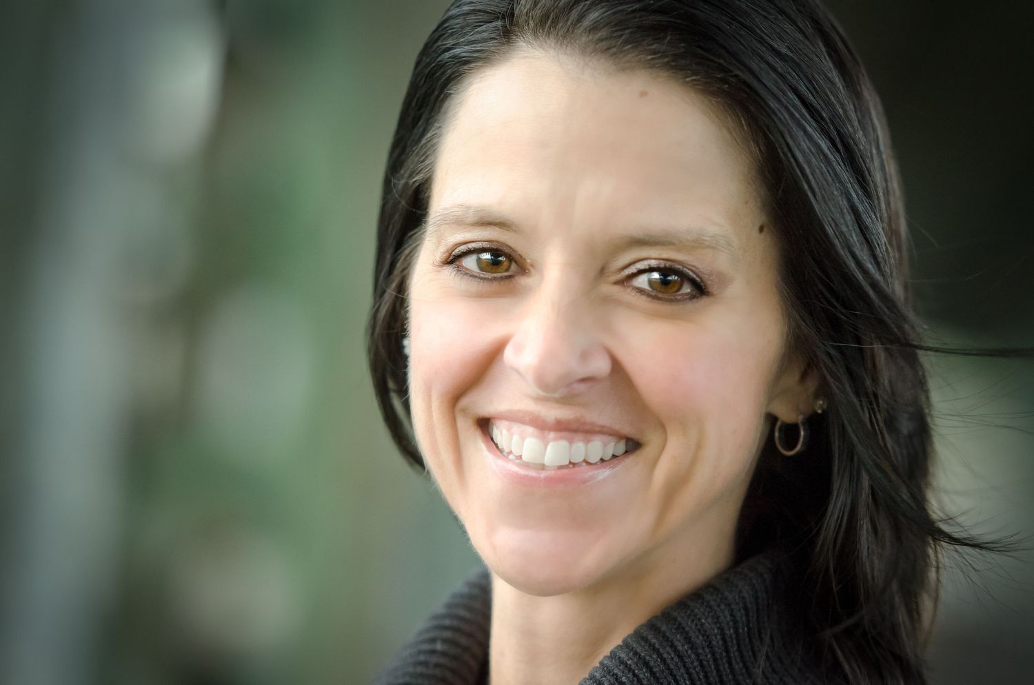 Close-up portrait of woman in black sweater with natural lighting.