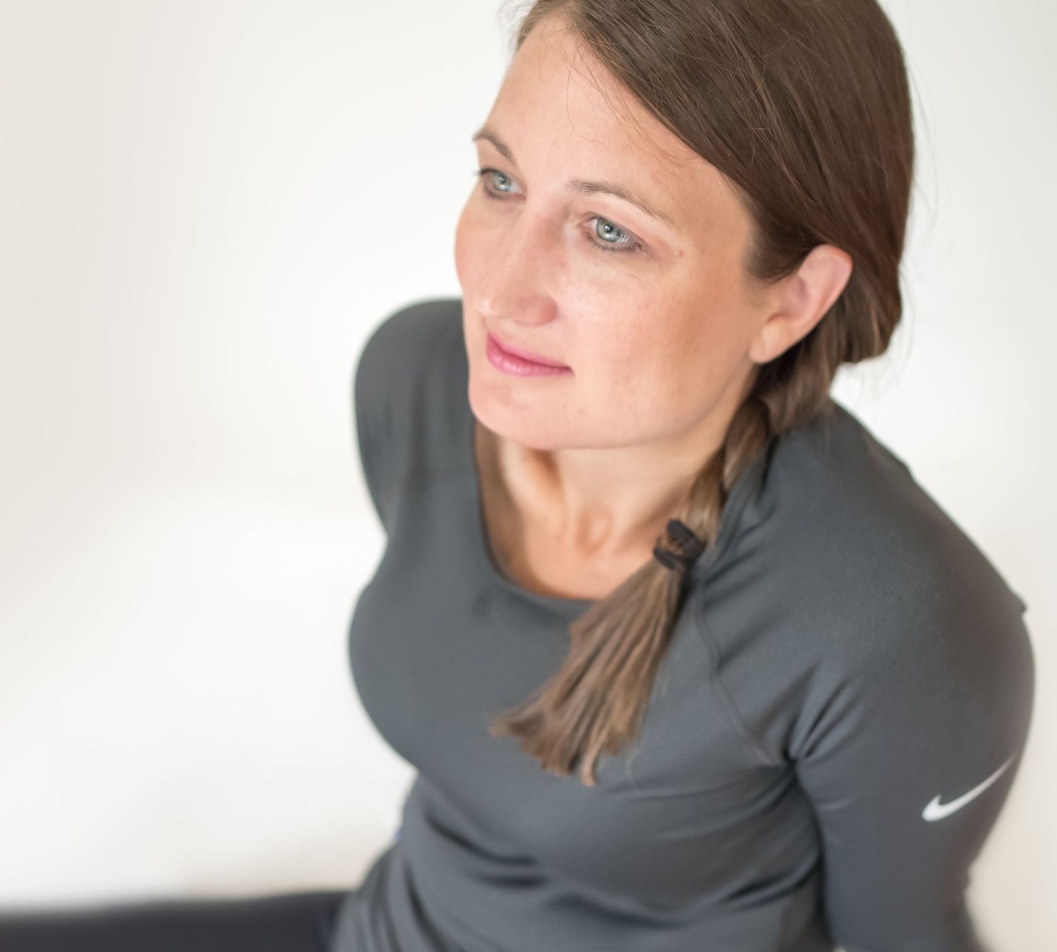 Woman in athletic wear with braided hair looking contemplatively to the side.