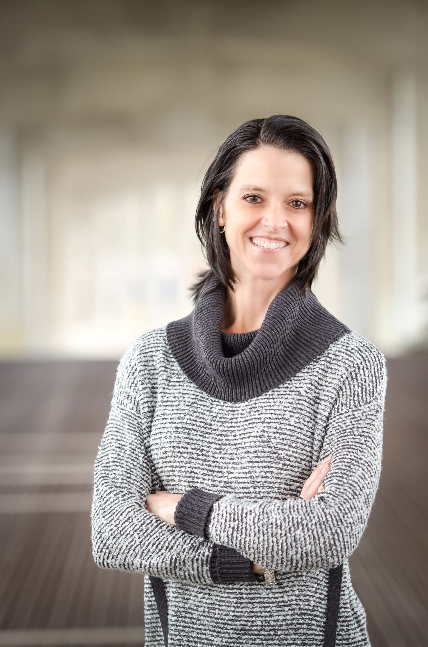 Professional business portrait of someone wearing a cozy gray turtleneck sweater with crossed arms.