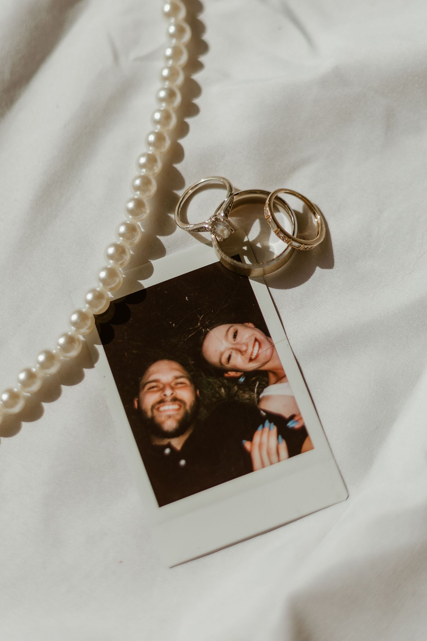 A Polaroid photo being held up in a car interior during sunset shows two people joyfully laughing together.