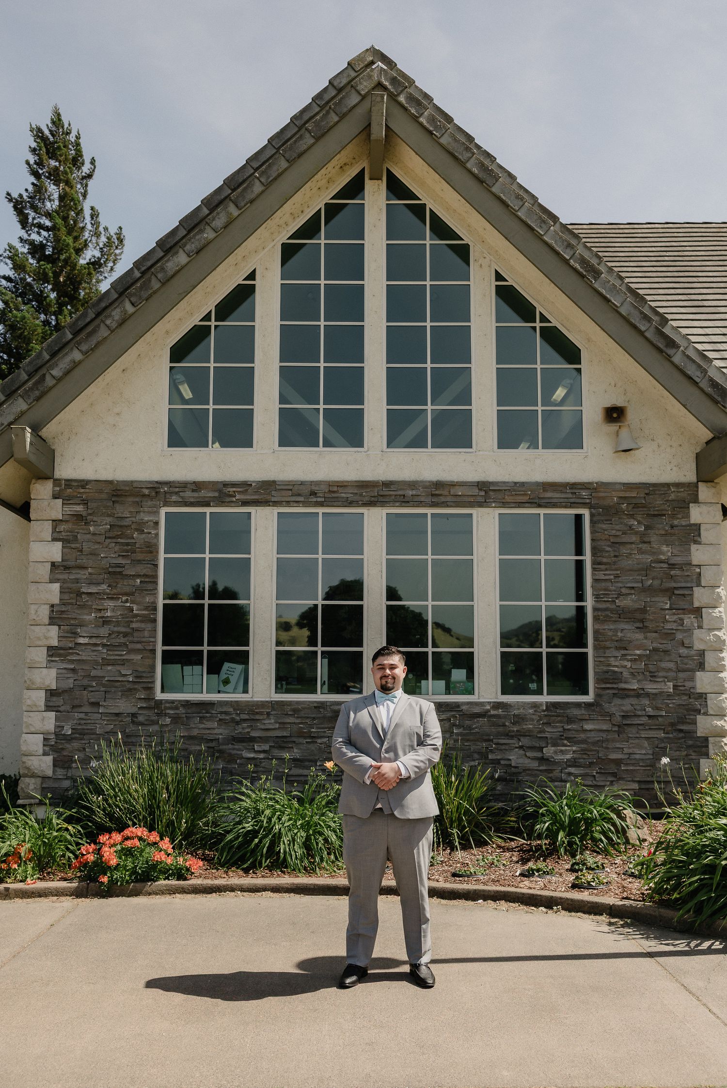Multiple connected images show someone standing in front of a modern stone and glass building on a sunny day.