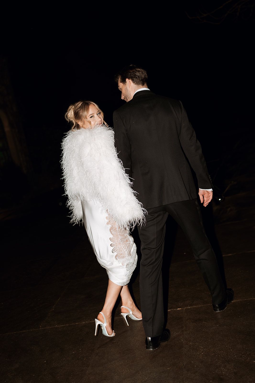 A couple shares an intimate moment on their wedding day in front of an elegant arched doorway with blue-framed windows.