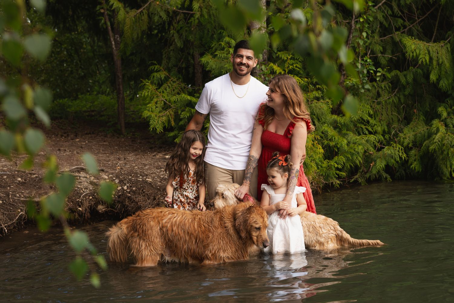 A family of 4 and their dogs pose for a photo in Lake Tapps during a family photography session.