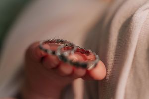 A close-up sequence showing a person's fingers holding and manipulating a small red and black insect.