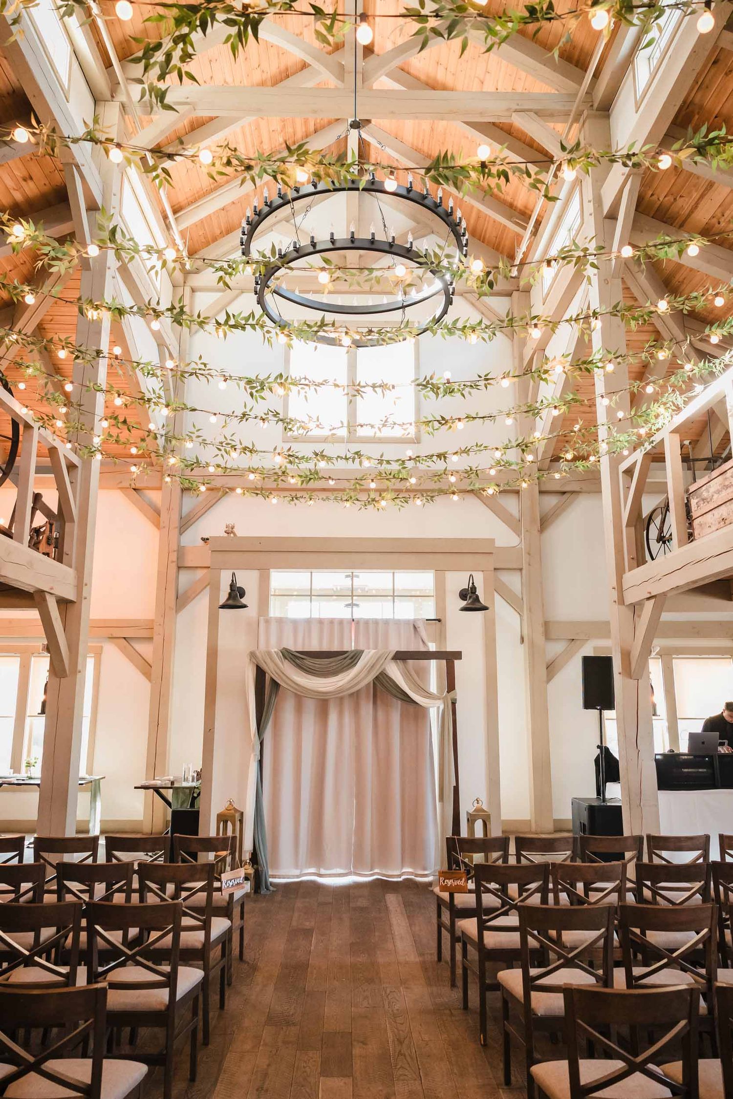 Indoor ceremony space at Briar Barn Inn with wooden beams, string lights, greenery, and wedding aisle setup