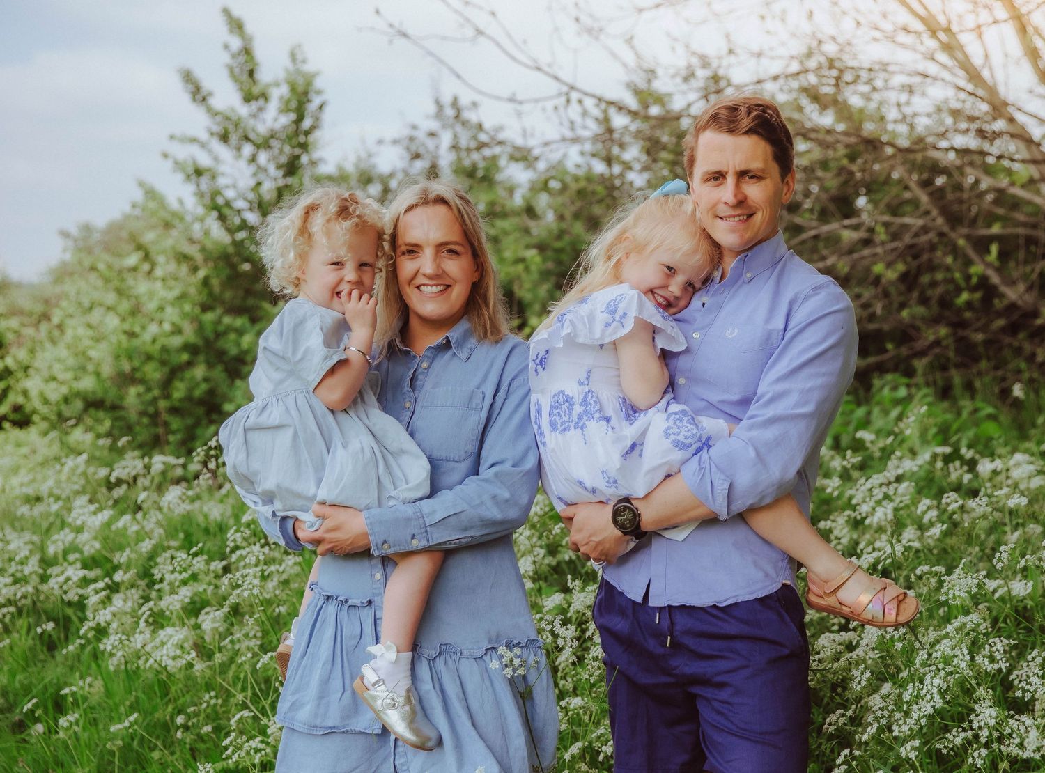 Family of four posing happily at a family photoshoot in Bexley in a sunflower field.
