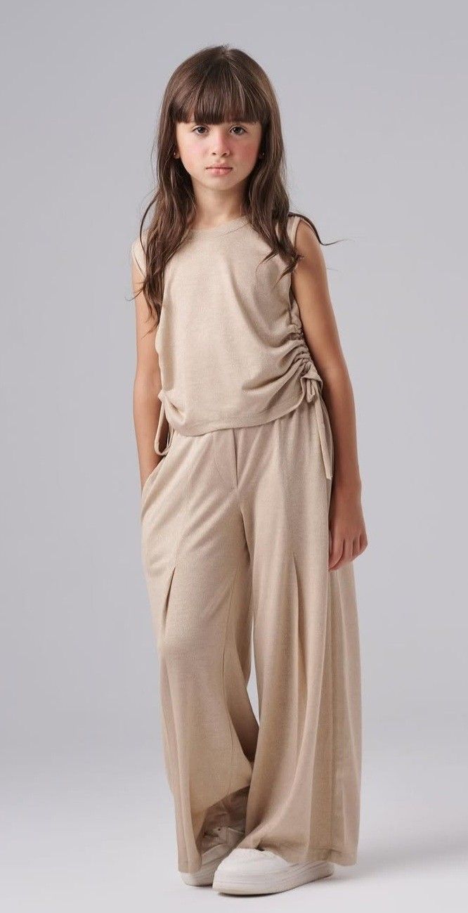 Girl wearing a beige sleeveless top with wide-leg matching pants and white sneakers.