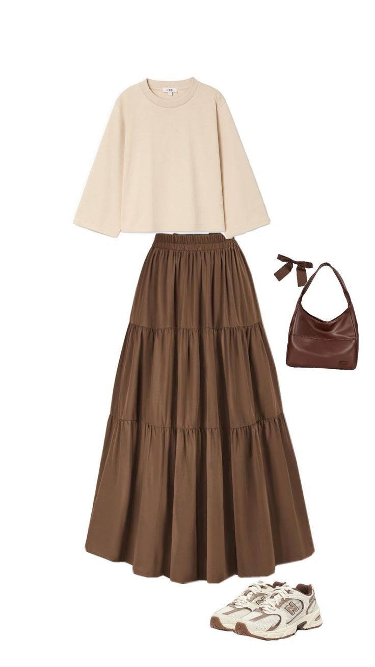 A casual outfit featuring a cream oversized tee, brown tiered maxi skirt, chunky sneakers, and a brown shoulder bag.