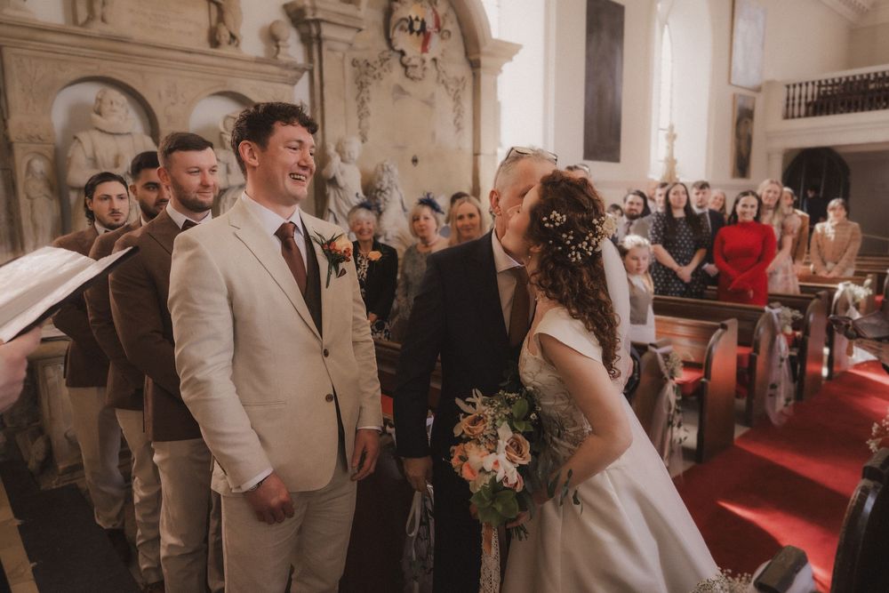 Bride and groom share a joyful moment at the altar during a church wedding ceremony with guests seated in pews.
