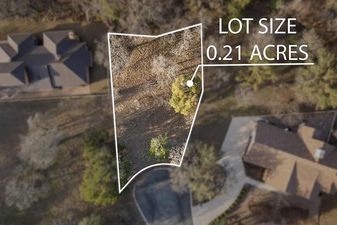 Aerial drone view of a 0.21-acre residential lot outlined in white, surrounded by trees and neighboring homes.