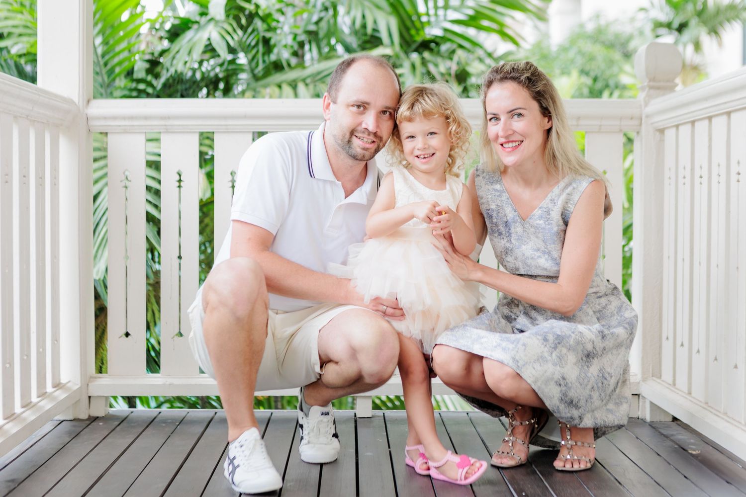 A Relaxed Family Photoshoot in a Singapore Condo. Russian caucasian couple with a blond child in light wooden balcony with green foliage