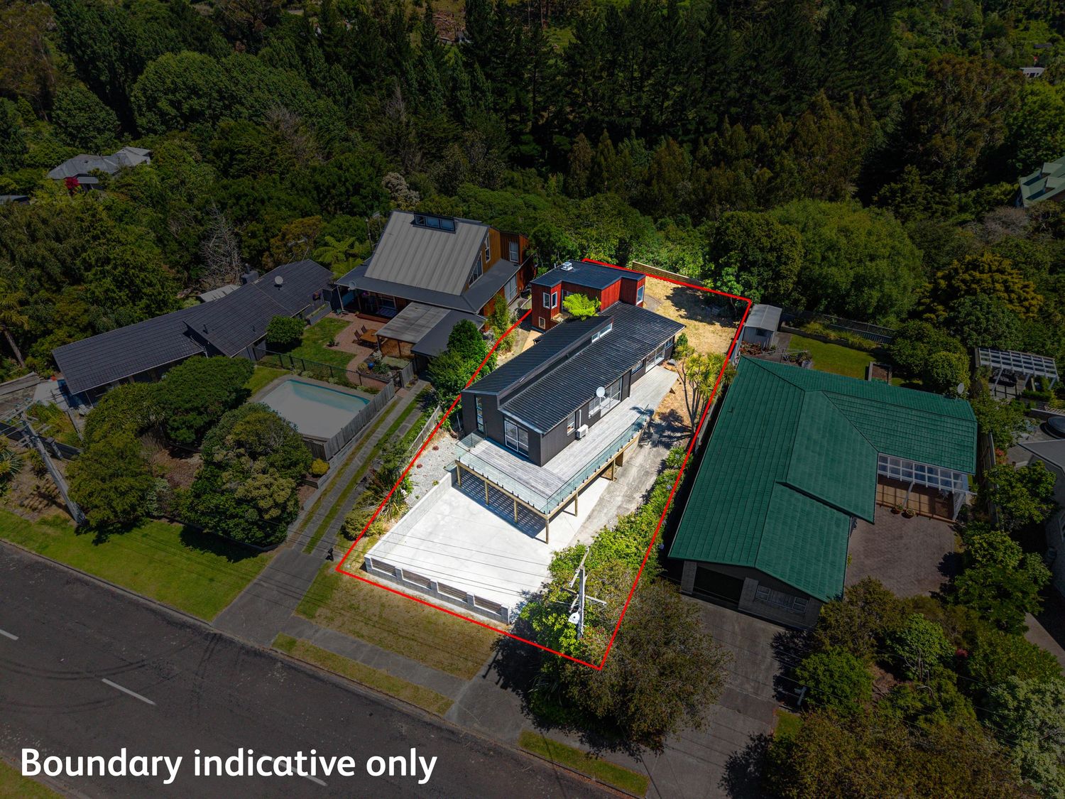 Aerial view of a modern black and white house with boundary lines marked, surrounded by lush green trees in a residential neighborhood.