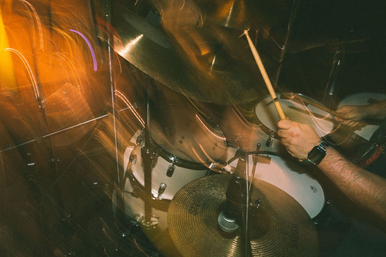 Close-up of drummer playing cymbals with drumsticks during live music performance.