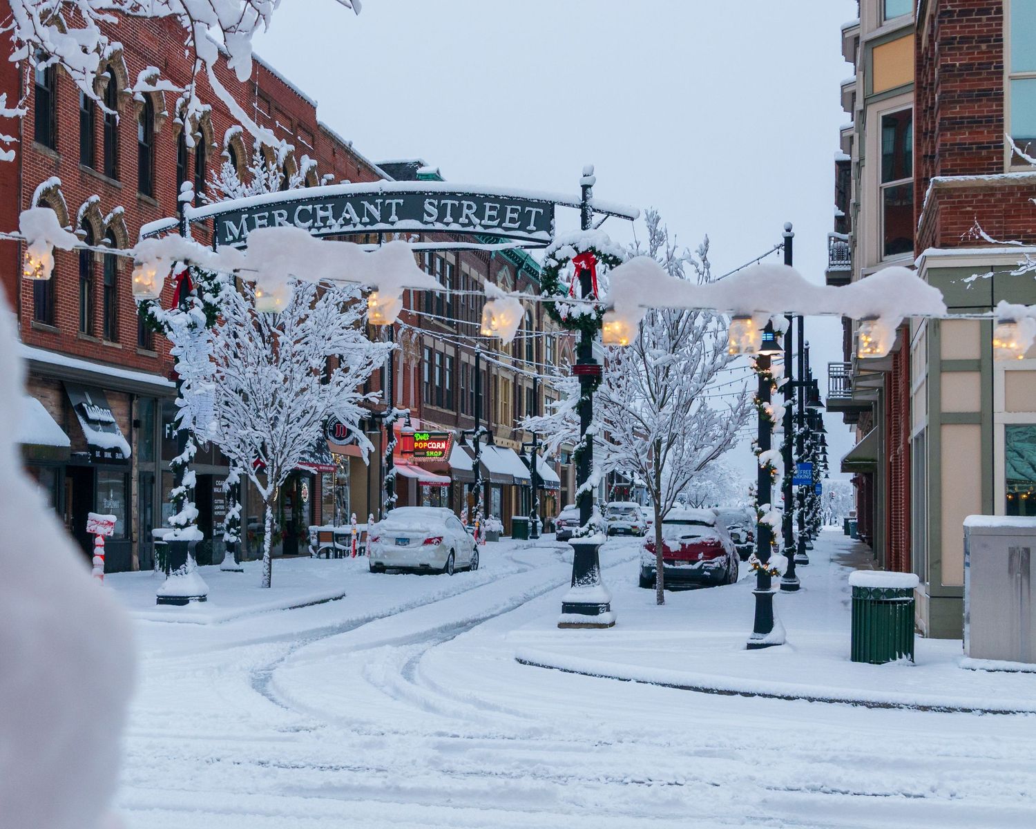 Snow-covered Merchant Street with festive lights and historic brick buildings in winter.