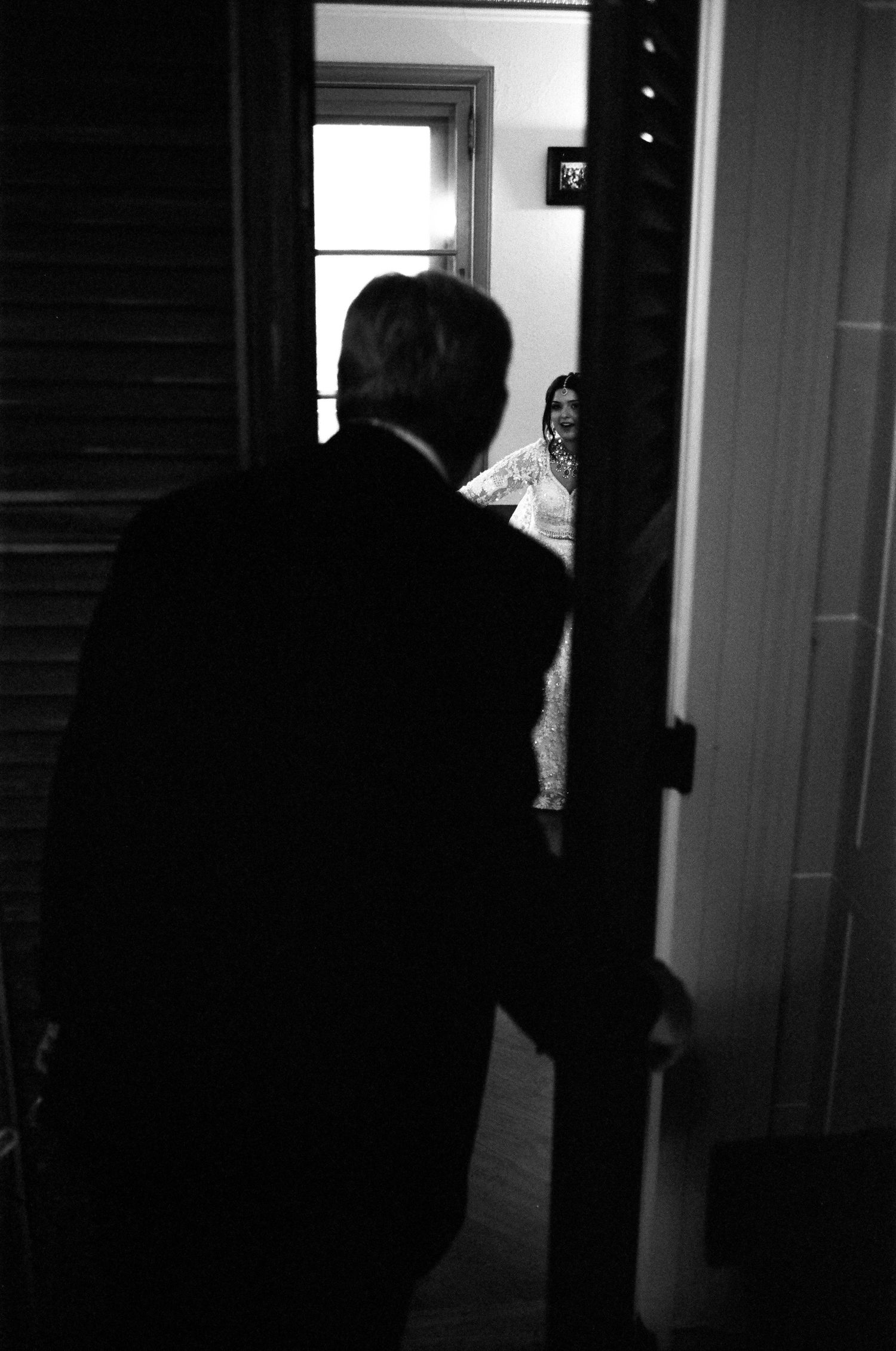 Black and white photo of  the father of the bride checking on her through a doorway on her wedding day at a Midwest Italian styled venue.