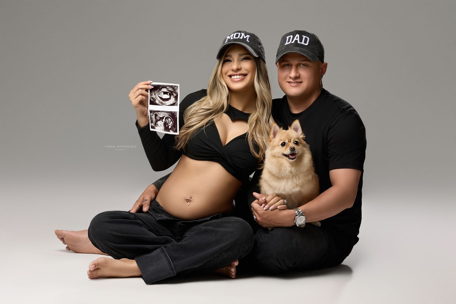 Beautiful maternity photo session in white off-shoulder dress against light background showing ultrasound images.