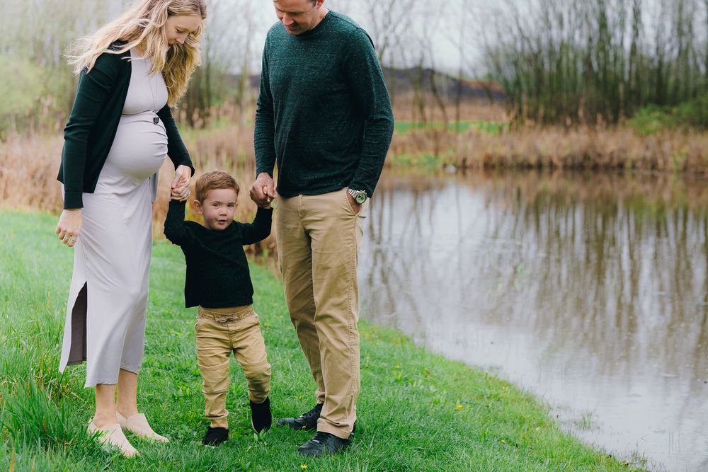 Family walking together near a pond with their small child in the middle holding their hands at Wood Hollow Metro Park in Hudson, Ohio