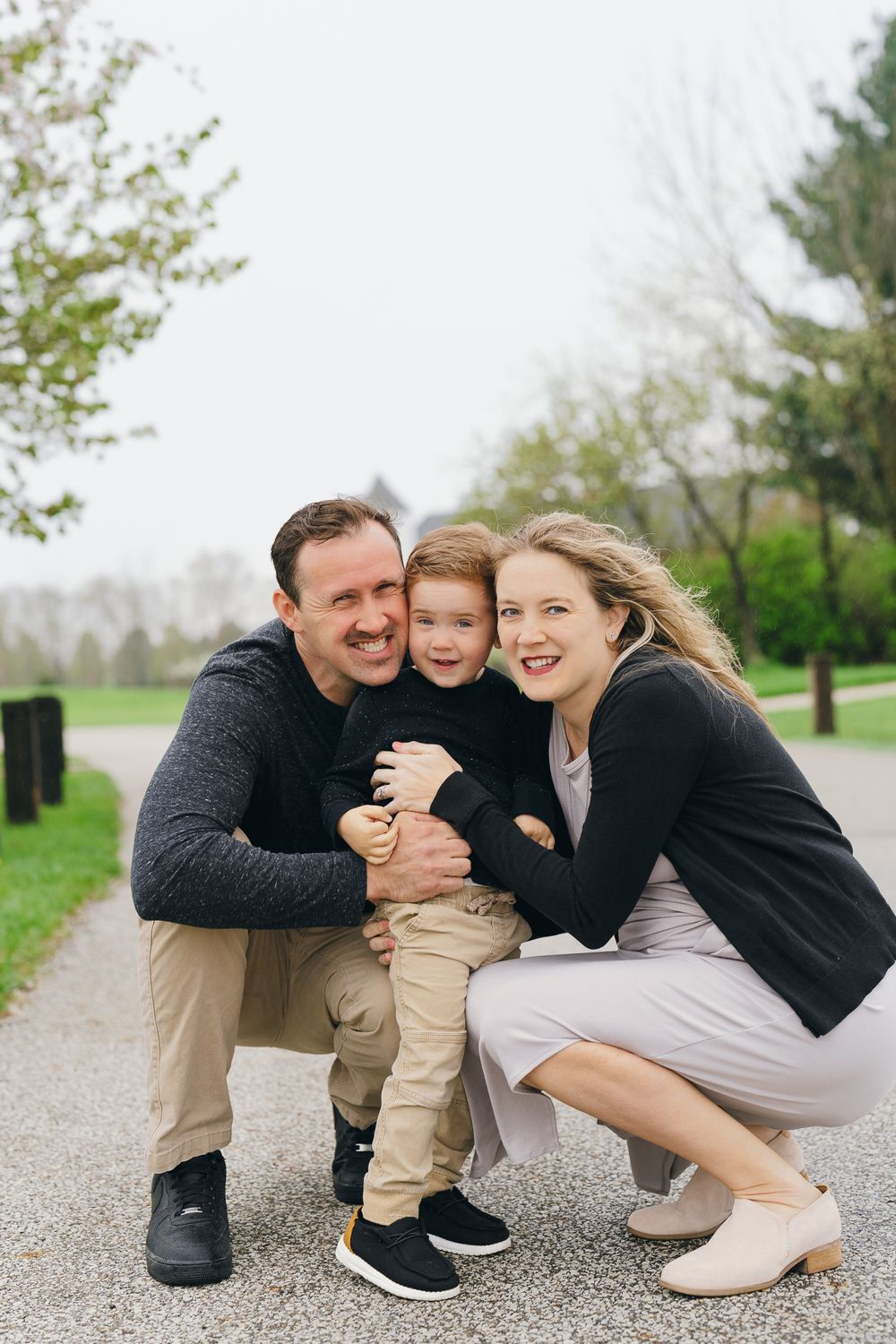 A happy moment captured as a family poses together on a walking trail surrounded by spring foliage at Barlow Road Farm Park in Hudson, Ohio.