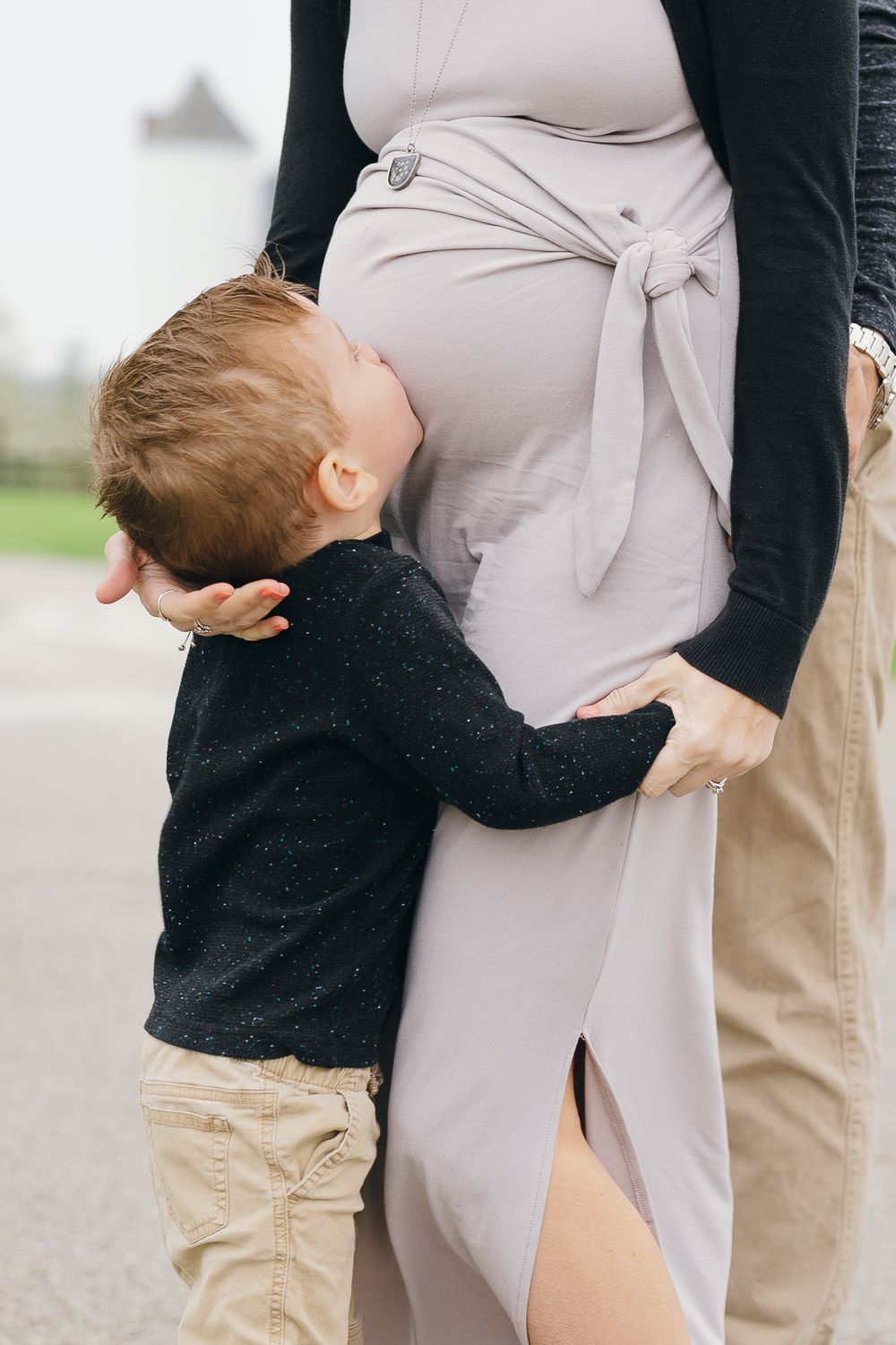 A maternity photo shoot showing a series of tender moments between expecting parents and a toddler in black and beige outfits in Hudson, OH