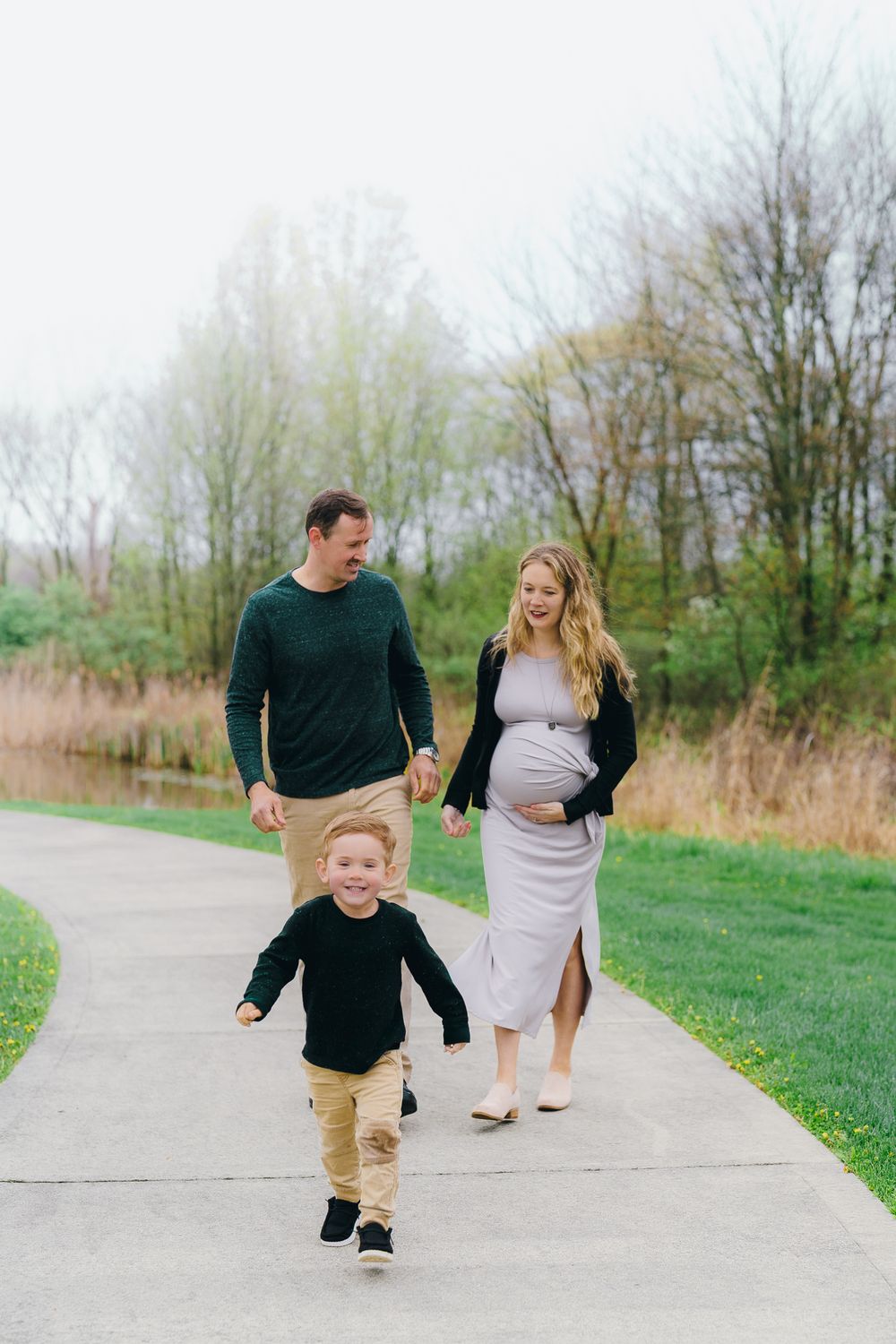Young family walking together on a pathway surrounded by grass and trees on a spring day at Wood Hollow Metro Park, Hudson, OH Maternity