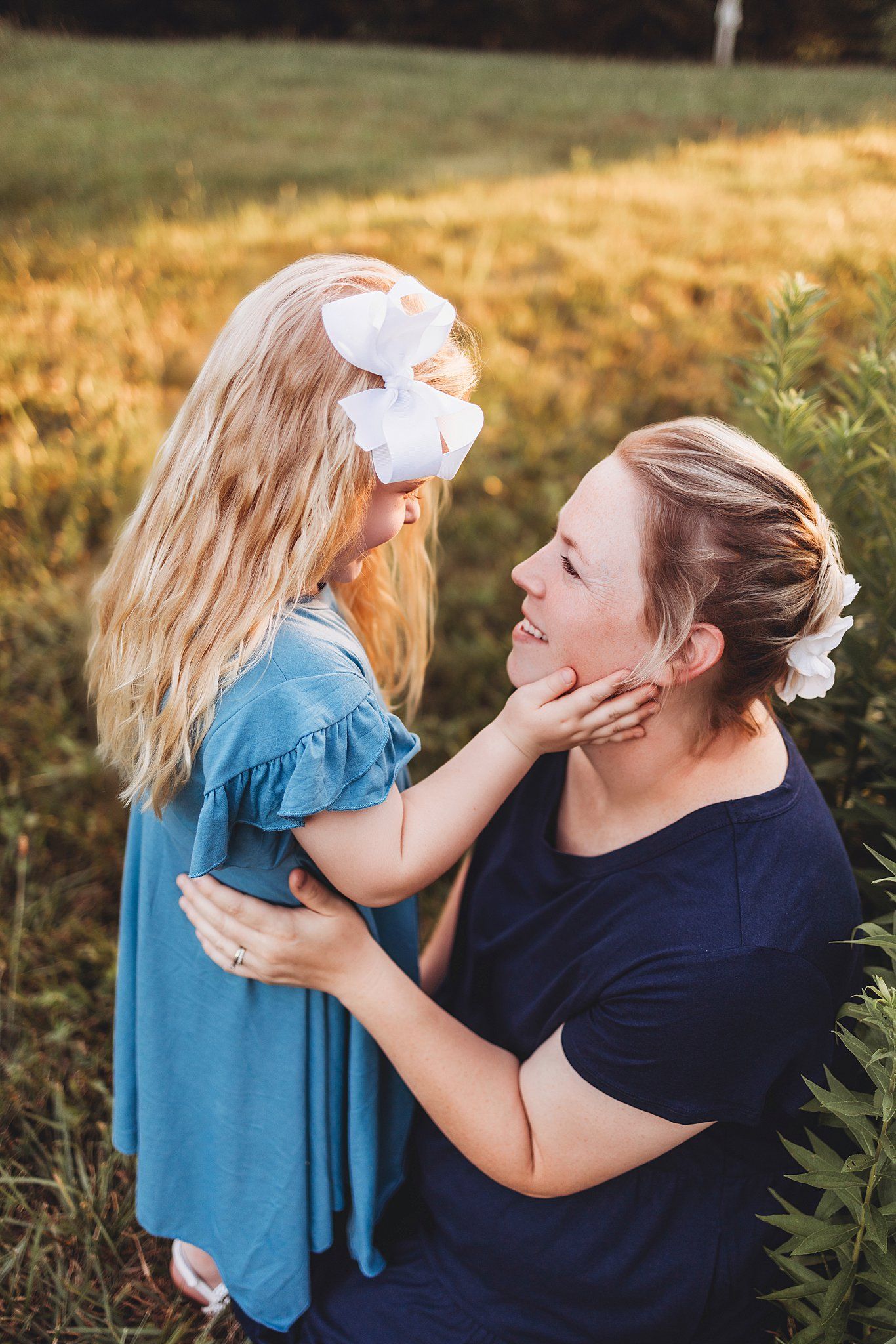 Sweet candid moment captured during golden hour in a grassy field, filled with playful energy and natural light.