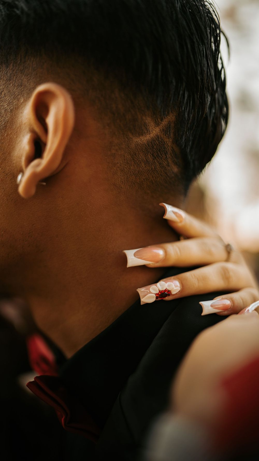 Close-up side view showing long acrylic nails with French tips against a dark background.