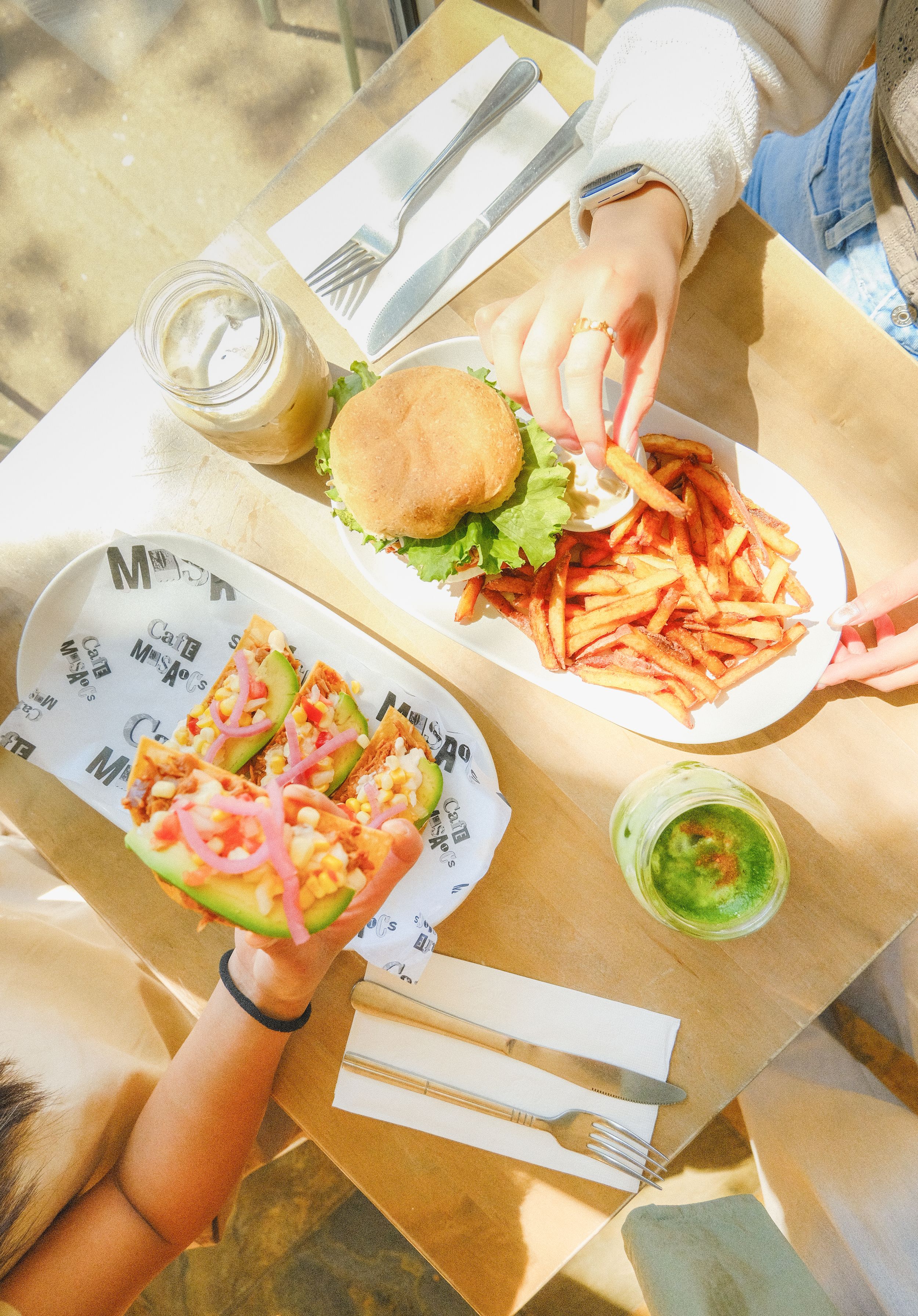 Overhead view of a casual lunch spread with burgers and french fries on brown paper at a restaurant table.